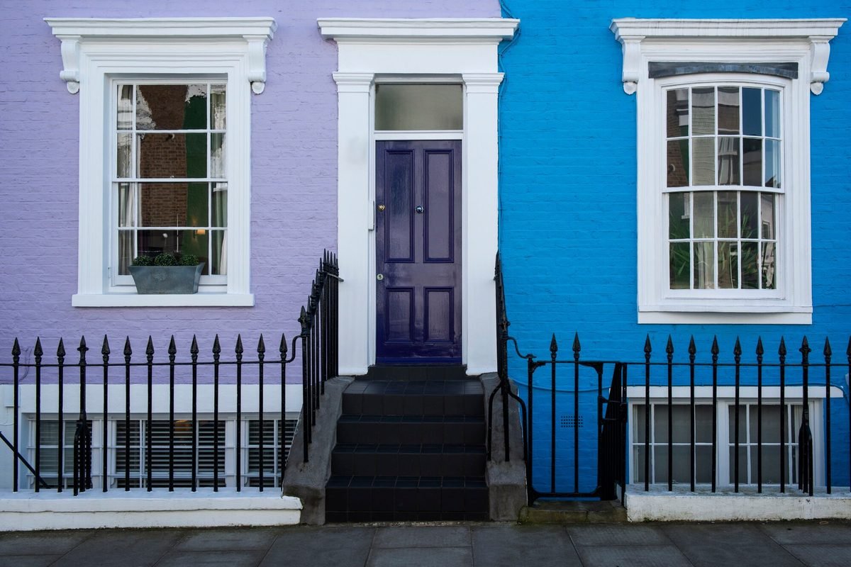 Boldly painted blue and lilac period terraced house fronts with a violet front door
