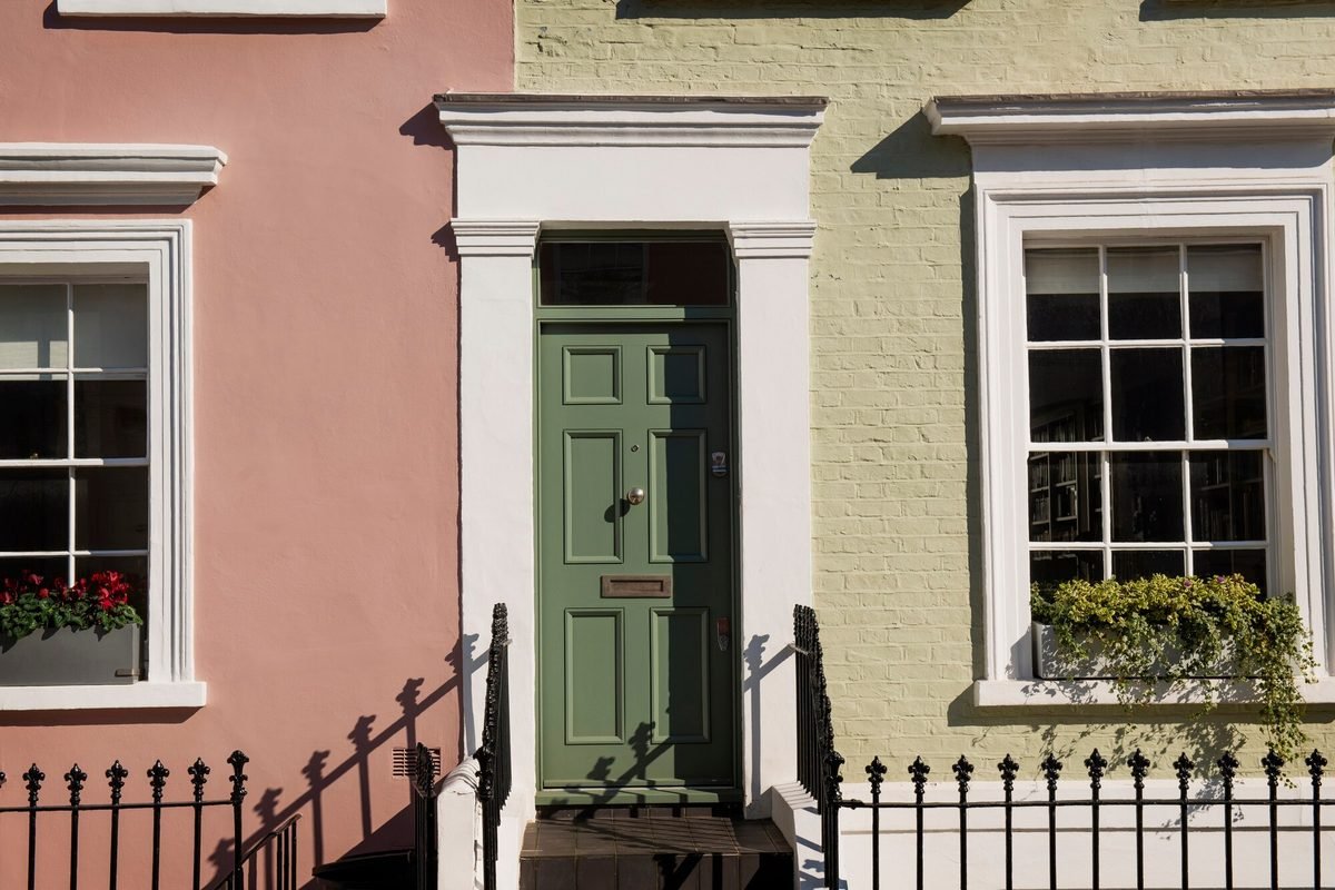 Freshly painted pastel render and a sage-green front door on a UK terraced house