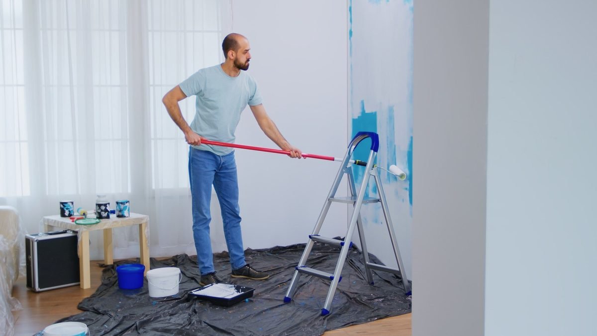 Decorator rolling fresh paint onto an interior living-room wall